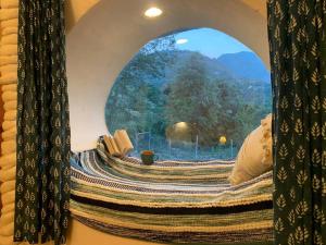 a window in a bedroom with a view of a mountain at Unique Mud Home With Scenic Mountain Views in Nainital
