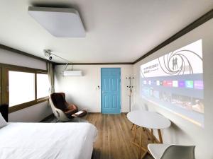 Top Island Hotel في جيجو: غرفة نوم بسرير وطاولة وباب ازرق