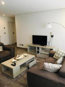 a living room with a couch and a tv at Incredible one bedroom space at East Legon in Accra