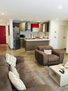 a living room with two couches and a kitchen at Incredible one bedroom space at East Legon in Accra