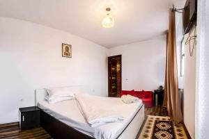 a bedroom with a bed with white sheets at Agropensiunea DarDen in Baia de Fier +52 photos