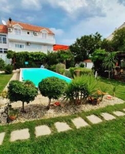 a garden with a swimming pool in front of a building at Rooms & Apartments Marinero in Betina