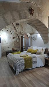 1 dormitorio con 1 cama grande en una pared de piedra en Il Geco, en Matera