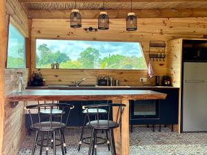 a kitchen with a counter with three bar stools at Ô Naturel Lodge Lifou in Lifou