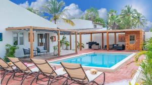 a villa with a swimming pool and chairs at Sunny Eagle Beach Villa - 3 min. from beach in Palm-Eagle Beach