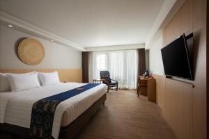 a hotel room with a bed and a flat screen tv at Aveta Hotel Malioboro in Yogyakarta