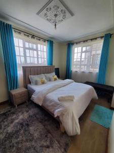 a bedroom with a large bed with blue curtains at Blissful Kisumu Milimani Haven in Kisumu