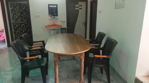 a wooden table with four black chairs around it at Sujata Buddha Homestay in Bodh Gaya