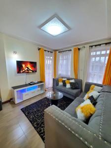 a living room with a couch and a tv at Blissful Kisumu Milimani Haven in Kisumu