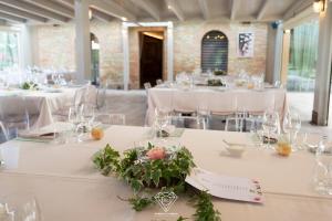 a room with white tables with glasses and flowers on them at La Rondanina in Castelnuovo Fogliani