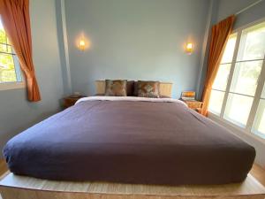 a large bed in a bedroom with two windows at Green Tree Cottage in Klong Muang Beach