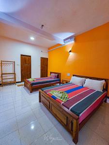 two beds in a room with yellow walls at Yoma Wild Hotel in Udawalawe