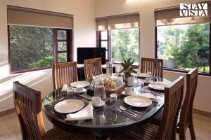 a dining room with a table and chairs and windows at StayVista at Vale Echoes - Breakfast Included in Munnar