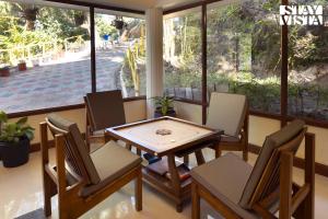 a dining room with a table and chairs and a window at StayVista at Vale Echoes - Breakfast Included in Munnar +20 photos