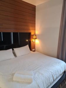 a bedroom with a white bed with a wooden wall at KL Q520 Premium Suite Room in Kuala Lumpur