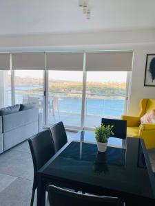 ein Wohnzimmer mit einem Esstisch und Blick auf das Wasser in der Unterkunft Sliema Seaview & seafront- APT 9, 49 Tigne Point Mansions in Sliema
