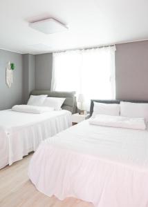 two beds in a room with white sheets at Goose Stay in Bucheon