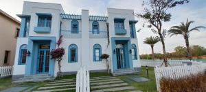 a blue and white house with palm trees and a fence at Villa NovawoRld Phan Thiết in Bình Sum