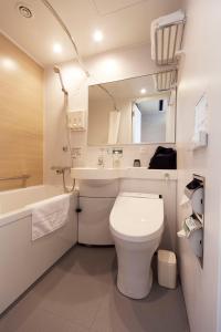 een badkamer met een toilet, een wastafel en een spiegel bij Kumamoto Washington Hotel Plaza in Kumamoto