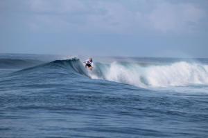 a person riding a wave on a surfboard in the ocean at Rihiveli Inn in Veymandoo