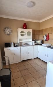 eine Küche mit weißen Schränken und einer Mikrowelle in der Unterkunft Sunrise Serenity Guest House in Lydenburg