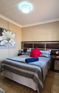 ein Schlafzimmer mit einem großen Bett mit roten und blauen Kissen in der Unterkunft Sunrise Serenity Guest House in Lydenburg