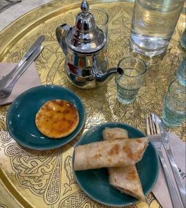 stolik z dwoma talerzami jedzenia i czajnik do herbaty w obiekcie DAR LALLA Aicha 2 w mieście Rabat