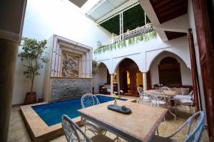 - un salon avec une table, des chaises et une piscine dans l'établissement Riad Oum B&B, à Marrakech