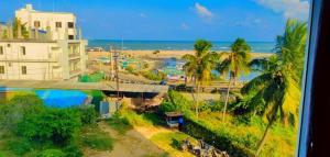 uma vista para uma praia com palmeiras e um edifício em Sri Gnana Vedha Beach Residency em Velānganni