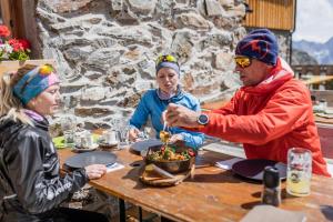 a group of people sitting at a table eating food at Pension Alpin in Mandarfen
