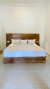 1 dormitorio con cama de madera con sábanas y almohadas blancas en Mellow Yellow en Ahangama