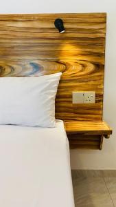 1 cama con cabecero de madera y almohada blanca en Mellow Yellow en Ahangama