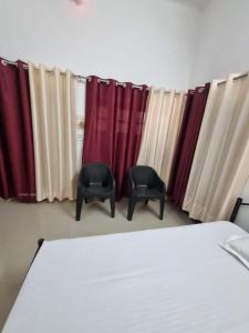 a bedroom with red and white curtains and two chairs at Krishna Homestay in Faizābād