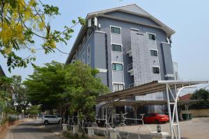 un edificio alto con una macchina rossa parcheggiata di fronte di Chonlapruk Lakeside Hotel a Ban Si Than