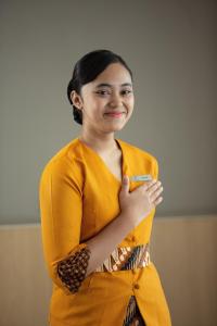 uma mulher num vestido amarelo de pé com os braços cruzados em Aveta Hotel Malioboro em Yogyakarta