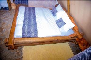 un letto in legno con lenzuola e cuscini bianchi di Boma Simba Safari Lodge a Voi