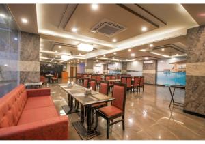 un restaurante con mesas y sillas y un bar en Kusum House, en Greater Noida