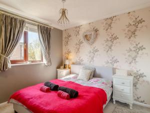 1 dormitorio con 1 cama roja y 2 almohadas en 3 Bed in Dereham 87159 en East Dereham