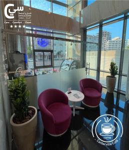 C - Hotel and Suites Doha في الدوحة: غرفة بها كرسيين أرجوانيين وطاولة