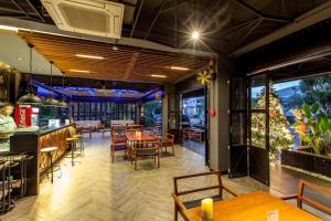 a restaurant with tables and chairs and windows at Loft Mania Boutique Hotel in Chumphon
