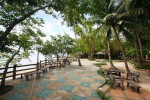 a group of benches sitting on a patio near the water at San Remigio Beach Club in San Remigio