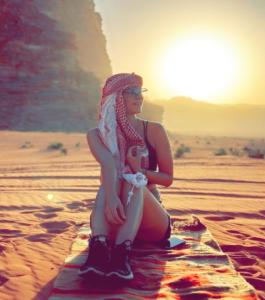 a woman sitting on the sand in the desert at Desert stars in Wadi Rum