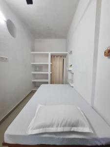 a white bedroom with a bed and white shelves at Krishna Homestay in Faizābād