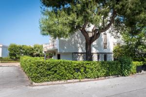 Una casa blanca con un árbol delante. en M085 - Marcelli, trilocale con giardino al Residence MARE VERDE, en Marcelli