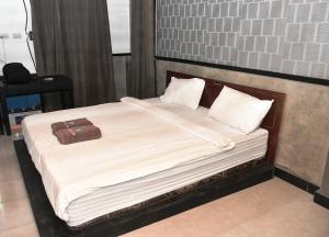 1 cama grande con sábanas blancas y almohadas. en Oseda Nias Surf House, en Hilibotodane