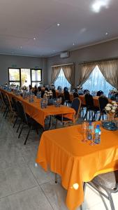 a large banquet hall with orange tables and chairs at LALA POA GUEST HOUSE in Klerksdorp