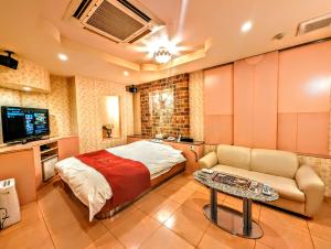 1 dormitorio con cama, sofá y TV en ホテル　ネグレスコ, en Amagasaki