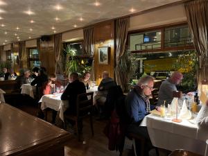 een groep mensen die aan tafel zitten in een restaurant bij Logis Hotel Du Midi in La-Roche-en-Ardenne