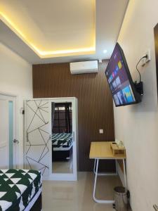 a room with a bed and a tv on a wall at Justin Guest House in Jimbaran