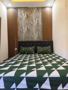 a bedroom with a bed with a green and white comforter at Justin Guest House in Jimbaran